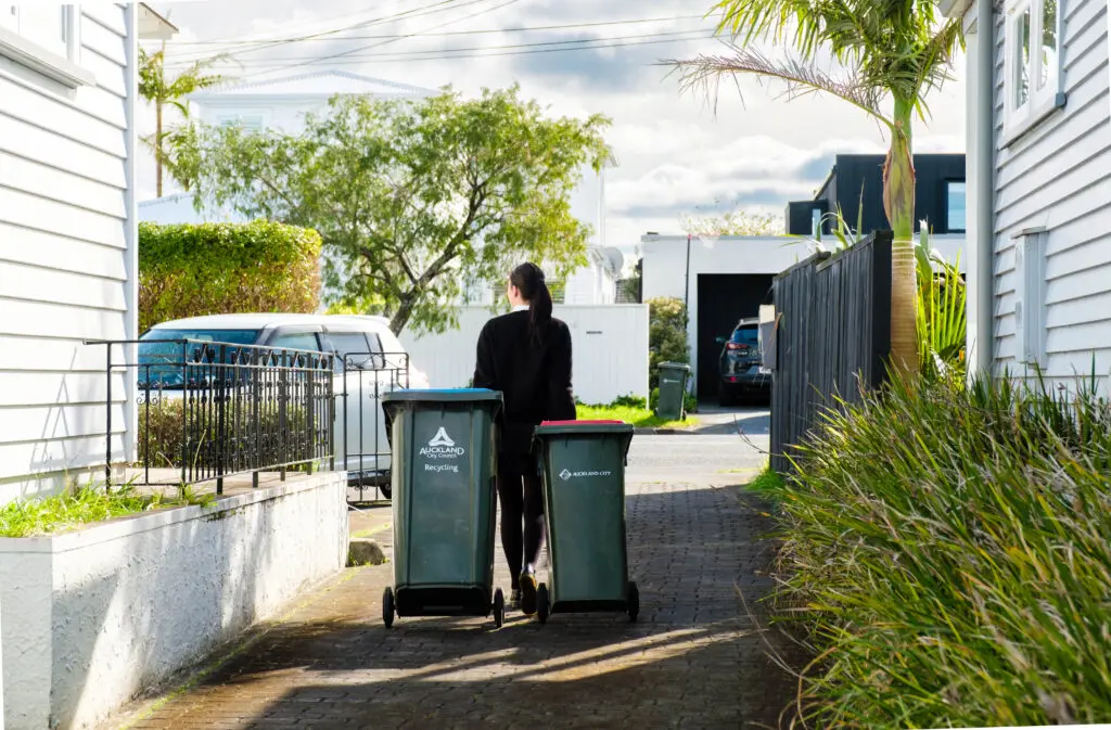 A lady taking out rubbish bins to the driveway